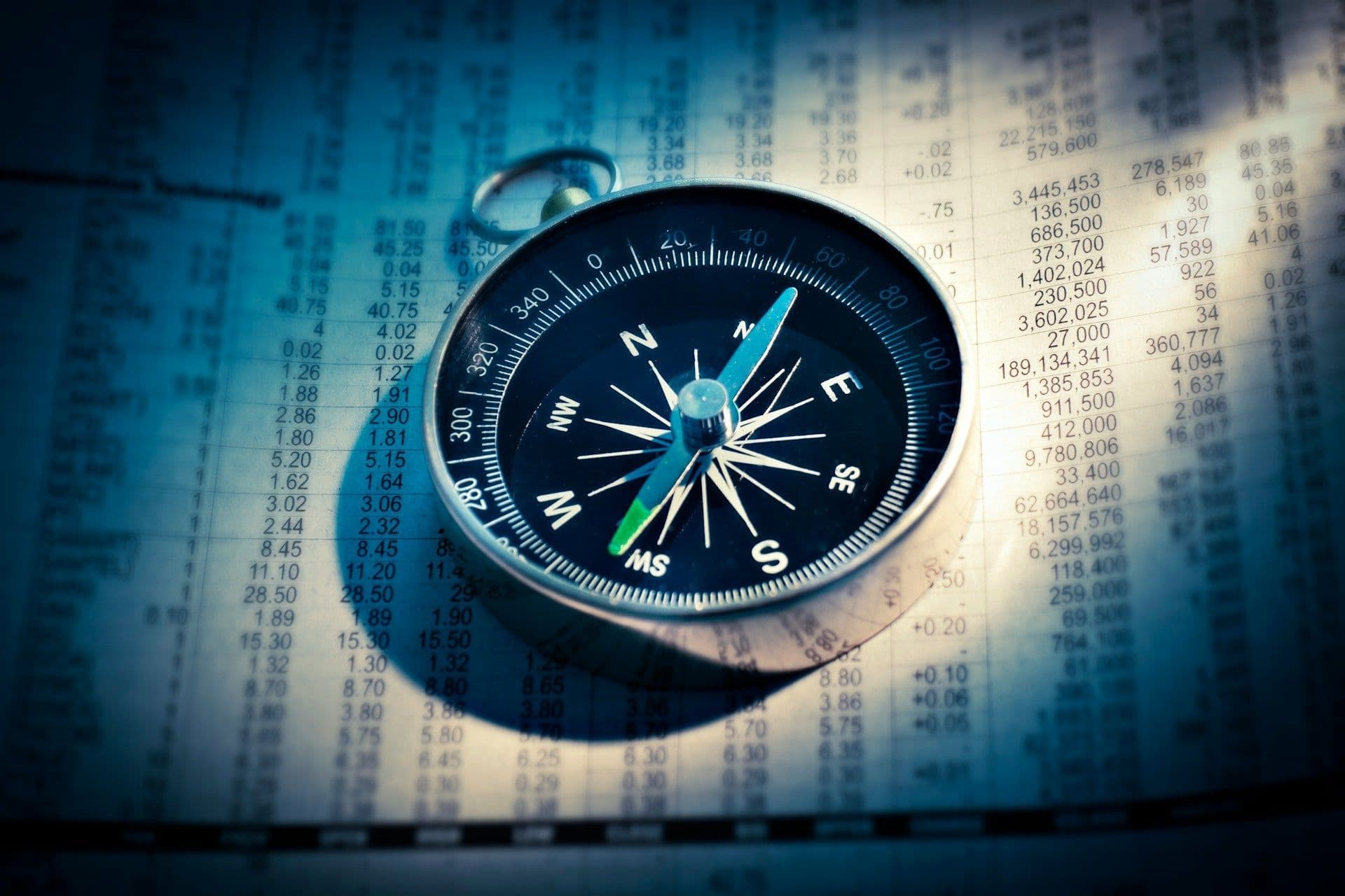 A compass resting on a page of financial figures.