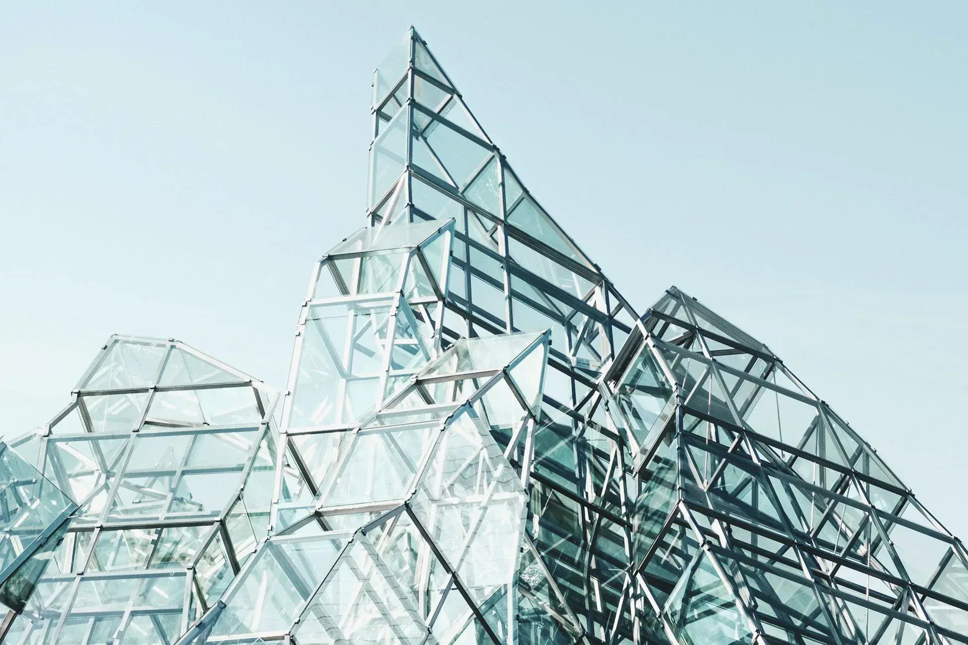 A faceted glass and steel structure against a pale sky.